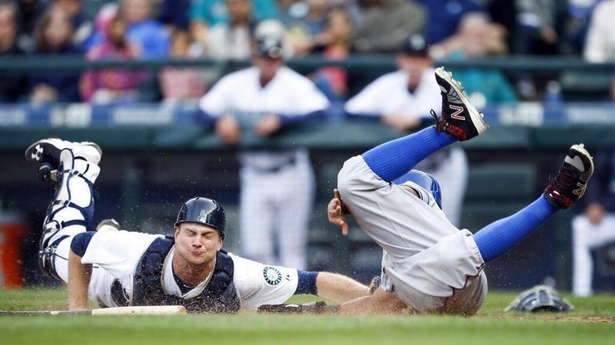 
Texas’ Rougned Odor, right, beats a tag by Mariners catcher John Hicksto score a run on a wild pitch during the seventh inning Monday at Safeco Field.

