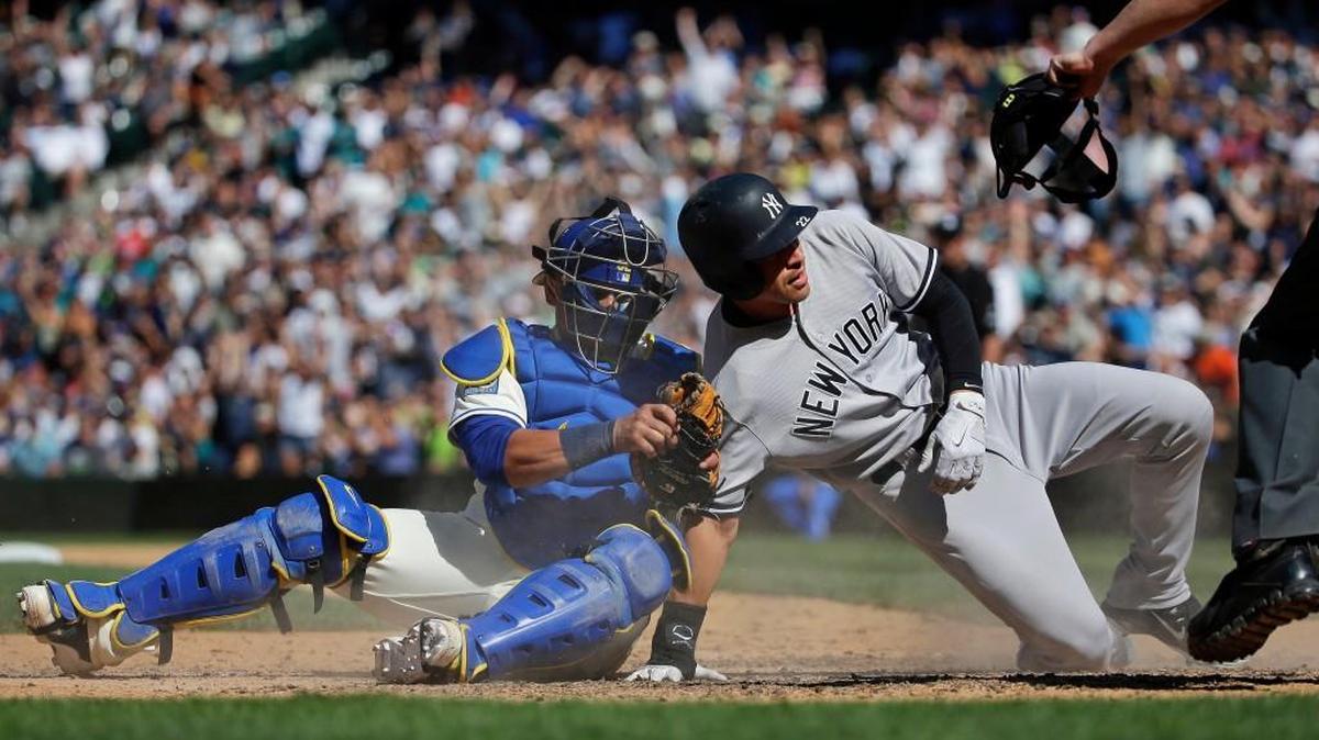 New York’s Jacoby Ellsbury is out at home on a tag Sunday by Seattle catcher Carlos Ruiz, left, while trying to score on a double hit by Chase Headley in the ninth inning in Seattle.