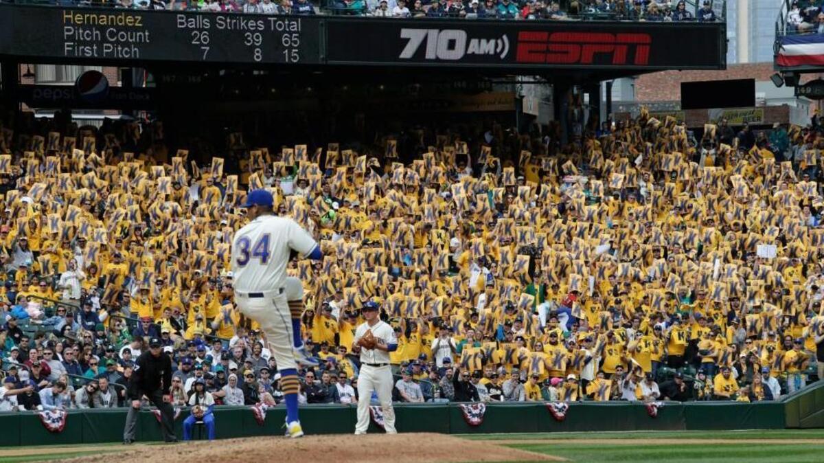 Seattle starting pitcher Felix Hernandez winds up against Oakland on Sunday during the fourth inning in Seattle. Fans, background, hold signs with the letter “K” for a strike, in the “King’s Court,” based on a nickname for Hernandez: “King Felix.” Hernandez struck out 10 in seven scoreless innings.