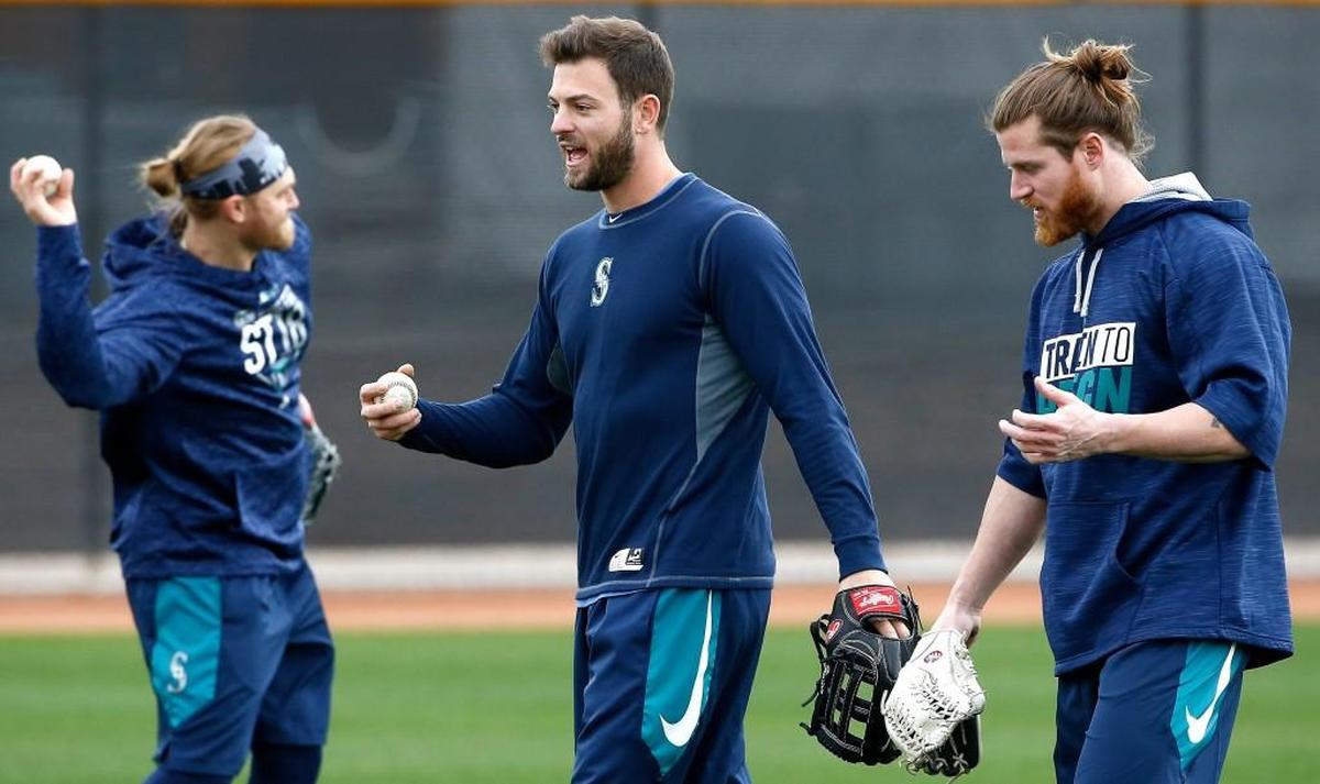 Seattle Mariners outfielder Mitch Haniger, center, talks with outfielder Ben Gamel, right, as infielder Taylor Motter, left, throws a baseball as the players do some informal workouts at the Mariners baseball spring training complex Wednesday, Feb. 14, 2018, in Peoria, Ariz.