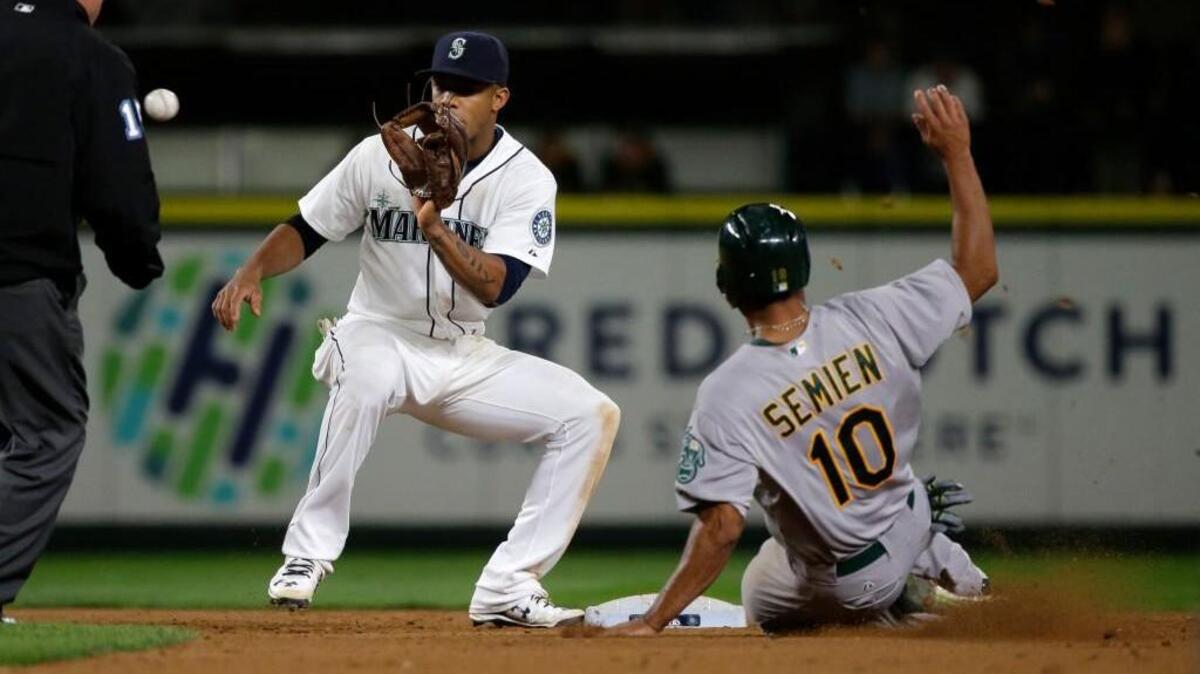 
Mariners shortstop Ketel Marte, left, makes the catch before tagging out the Athletics’ Marcus Semien as he tries to steal second base in the eighth inning Saturday. Semien ended up hitting the game-winning home run in the 13th inning as the A’s won, 7-5.
