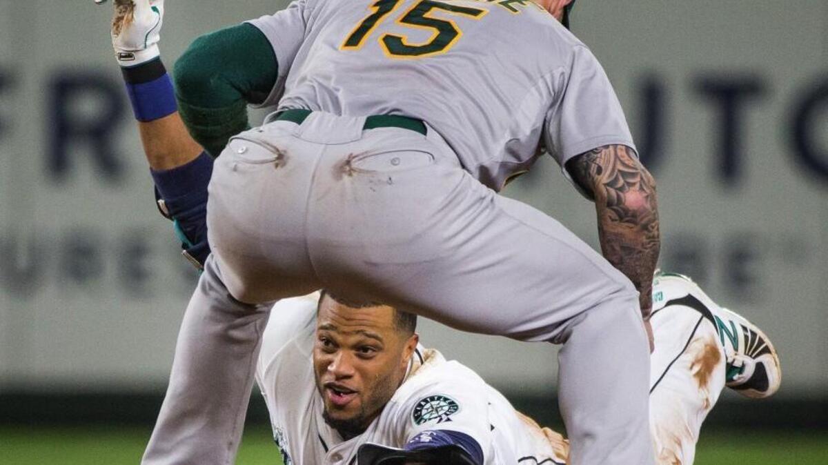 
The Mariners' Robinson Cano slides safely under the tag of Oakland shortstop Brett Lawrie (15) for a double in the seventh inning that made Cano the first player in MLB history to record 11 consecutive 30-double seasons to open a career.
