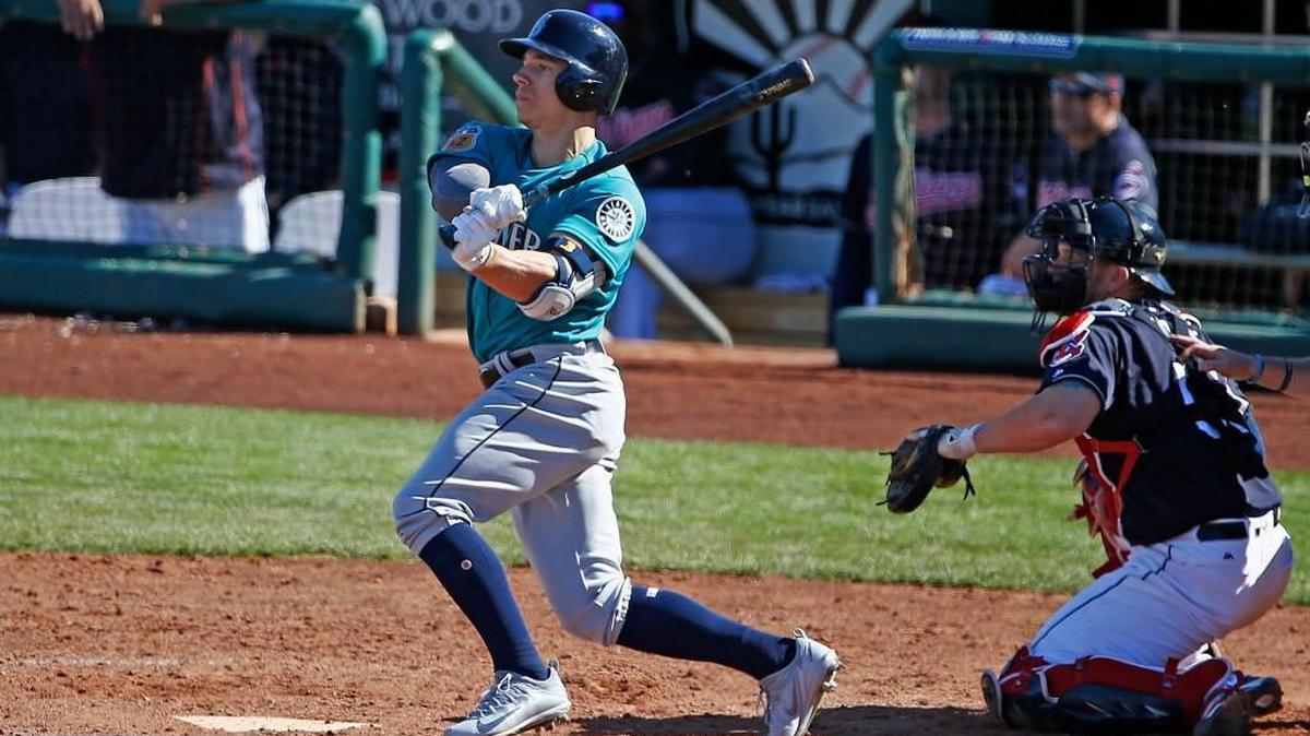 Seattle Mariners' Tyler O’Neill rockets a run-scoring double in spring training as Cleveland Indians catcher Yan Gomes watches. O’Neill will start this season in Triple-A with the Tacoma Rainiers.