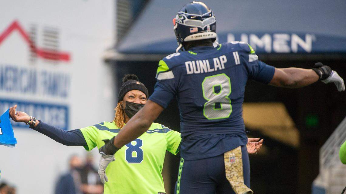 Seattle Seahawks defensive end Carlos Dunlap (8) runs out to hug his mother, Dr. Diana Ross-Jackson, during a timeout in the game against the Arizona Cardinals on Sunday at Lumen Field in Seattle. Dr. Ross-Jackson served 11 years in the United States Army Reserve as a 91E Dental Specialist and was recognized in front of the crowd as a celebration of United States military veterans.