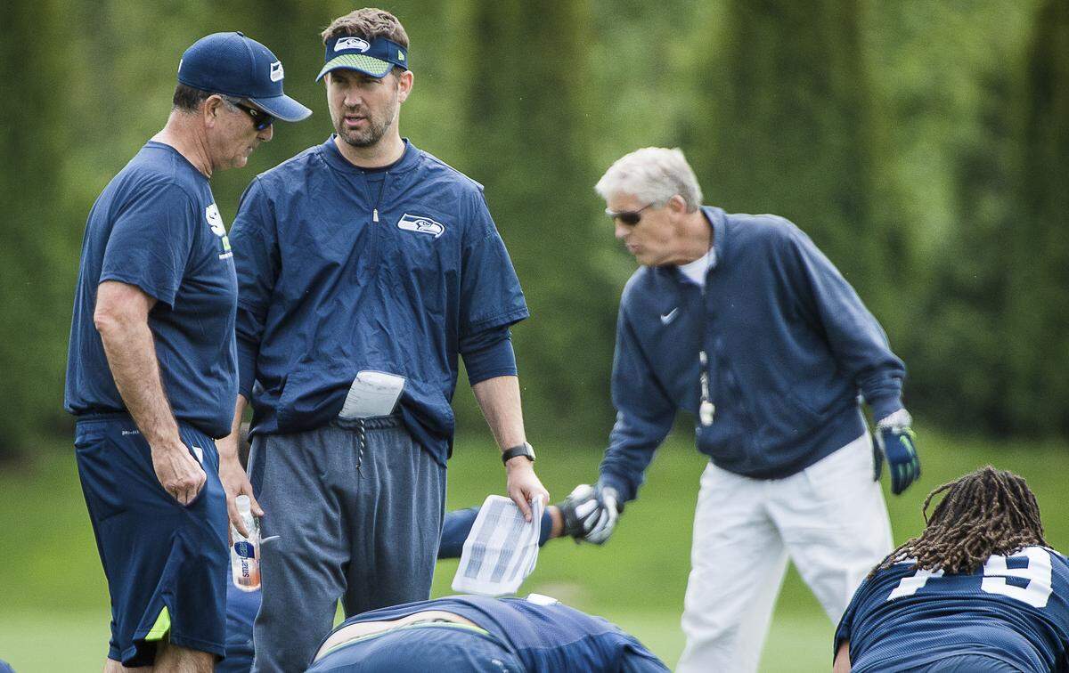 New Seahawks offensive line coach Mike Solari, left, talks with new offensive coordinator Brian Schottenheimer (center) with coach Pete Carroll in the background during rookie minicamp at the Virginia Mason Athletic Center in Renton last month.