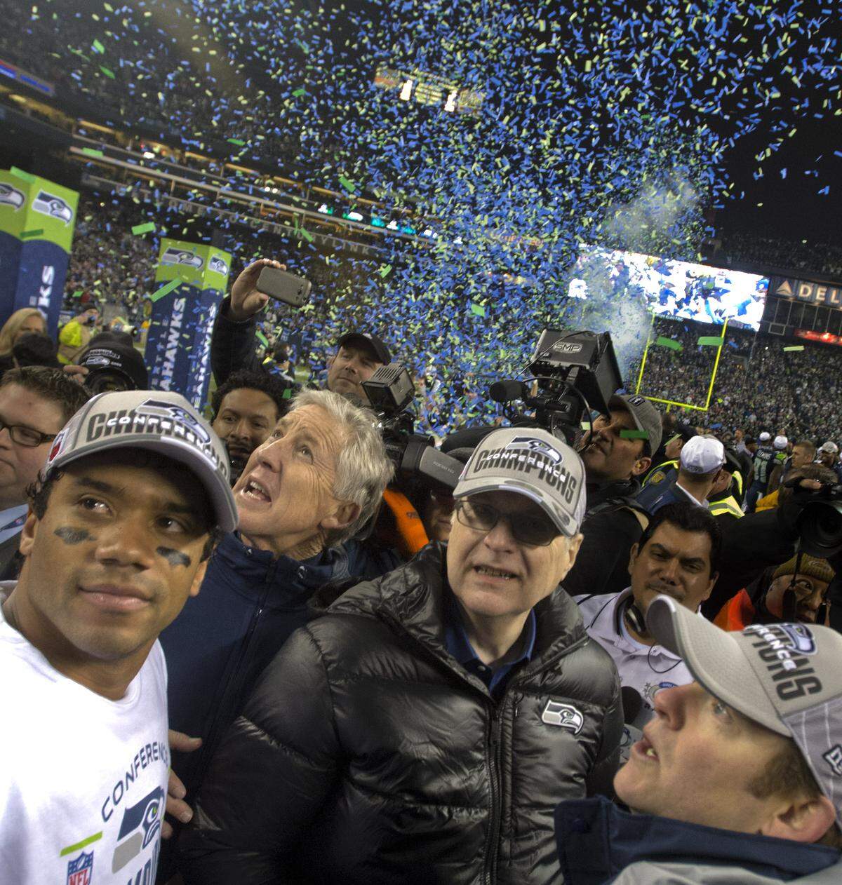 Seahawks quarterback Russell Wilson (far left) celebrates on the field with coach Pete Carroll (second from left), team owner Paul Allen (in black coat), and general manager John Schneider after Seattle beat San Francisco at CenturyLink Field to win the NFC championship on Jan. 19, 2014, to advance to the Super Bowl. Wilson remembers Frank Sinatra was playing in the background.