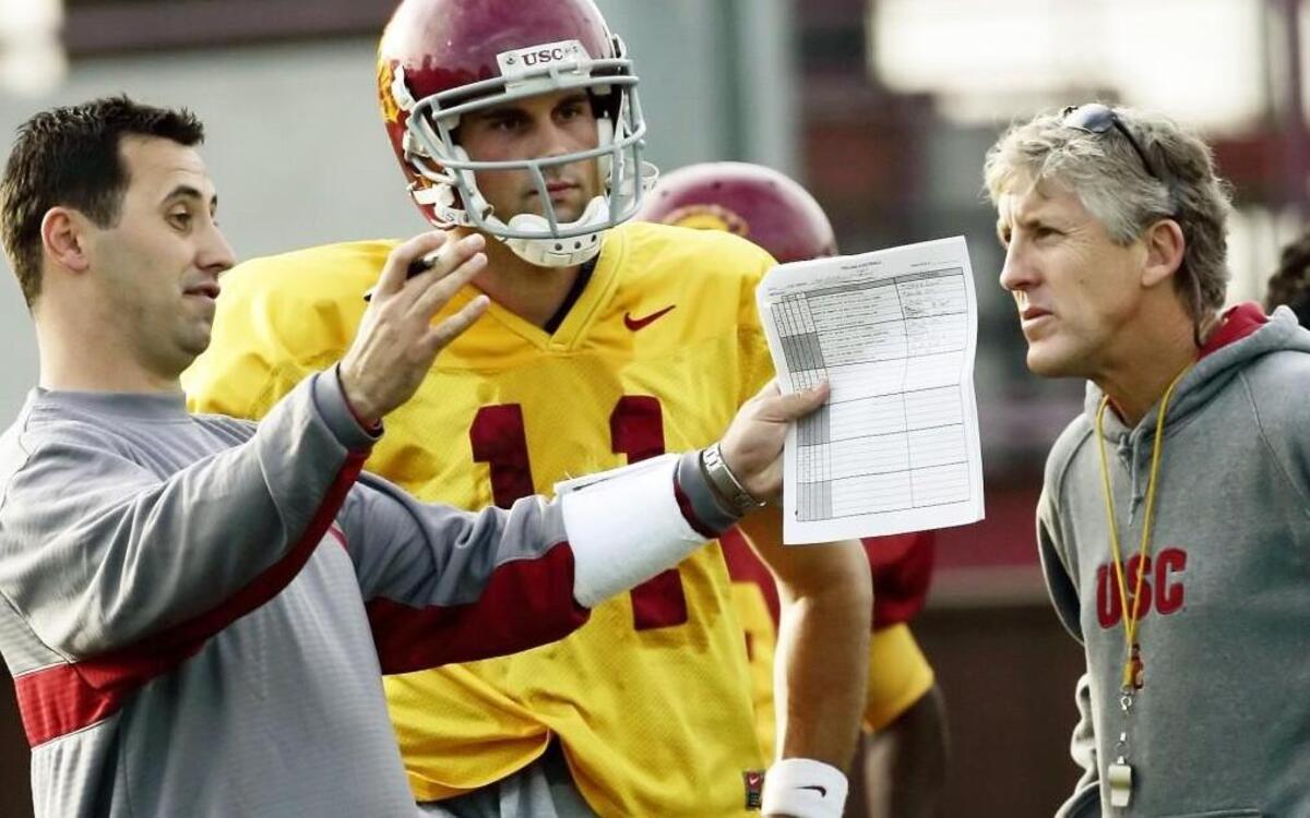
Former USC coach Pete Carroll, right, talks to then-assistant head coach Steve Sarkisian as quarterback Matt Leinart looks on. Sarkisian was fired by USC as head coach Monday.

