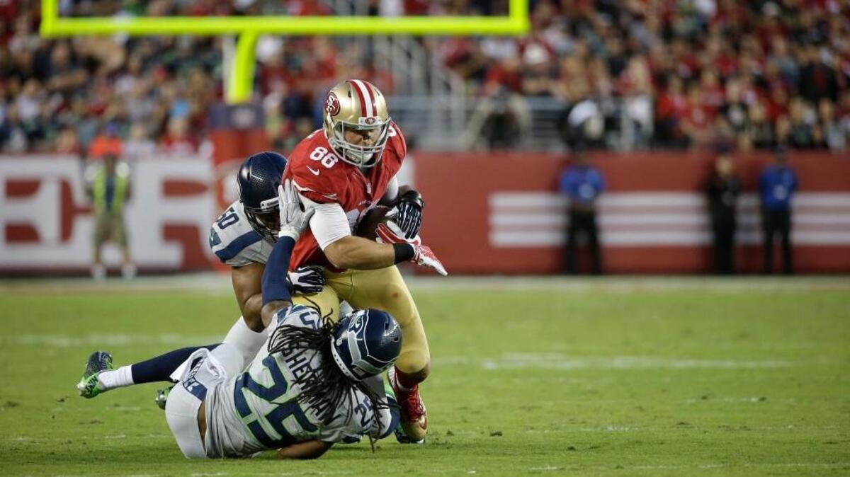 San Francisco 49ers tight end Garrett Celek (88) is tackled by Seattle Seahawks cornerback Richard Sherman (25) and outside linebacker K.J. Wright (50) during the first half of an NFL football game in Santa Clara, Calif., Thursday, Oct. 22, 2015.