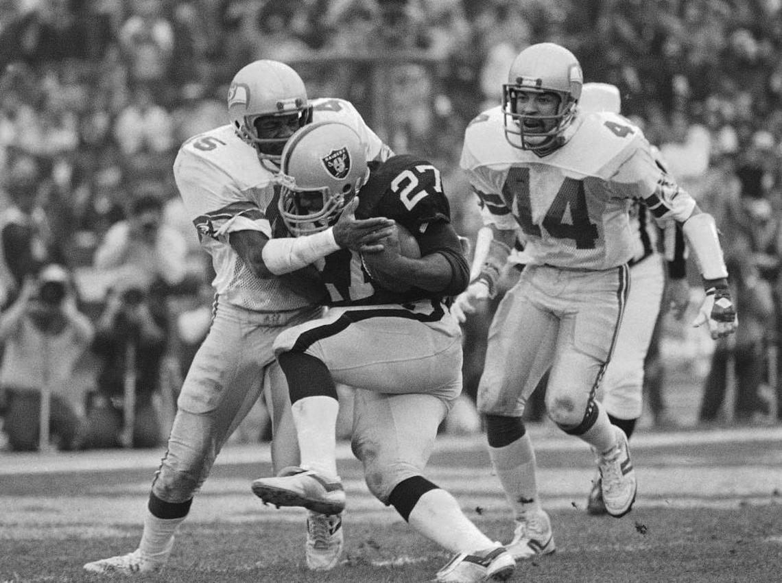 FILE - In this Jan. 8, 1984, file photo, Los Angeles Raiders running back Frank Hawkins (27) pushes his way across the goal line for his second touchdown of the day despite the defensive efforts of Seattle Seahawks’ Kenny Easley during an NFL football game in Los Angeles.