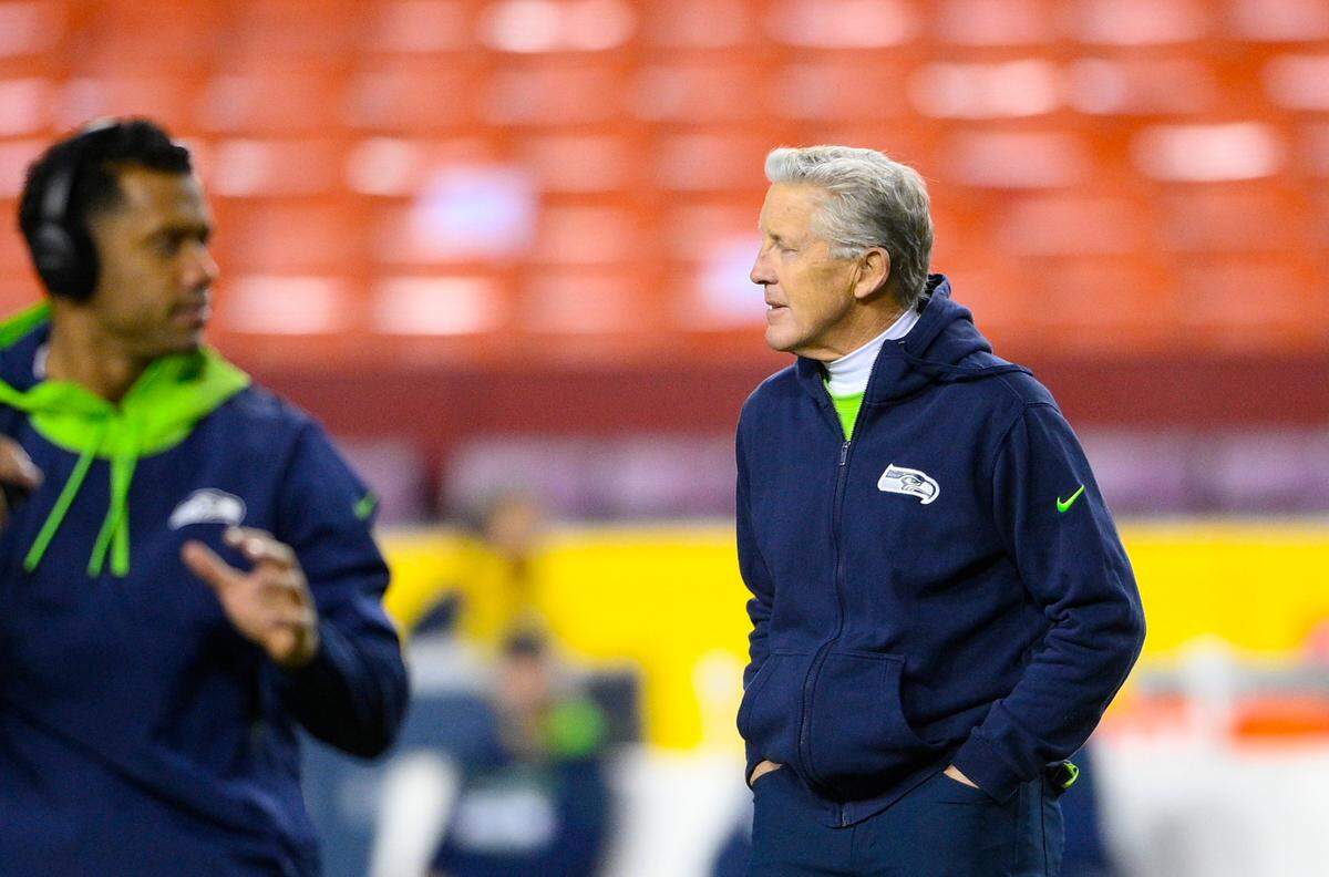 Seattle Seahawks head coach Pete Carroll, right, watches Seattle Seahawks quarterback Russell Wilson, left, warmup on the field prior to the start of the first half of an NFL football game against the Washington Football Team, Monday, Nov. 29, 2021, in Landover, Md. (AP Photo/Nick Wass)