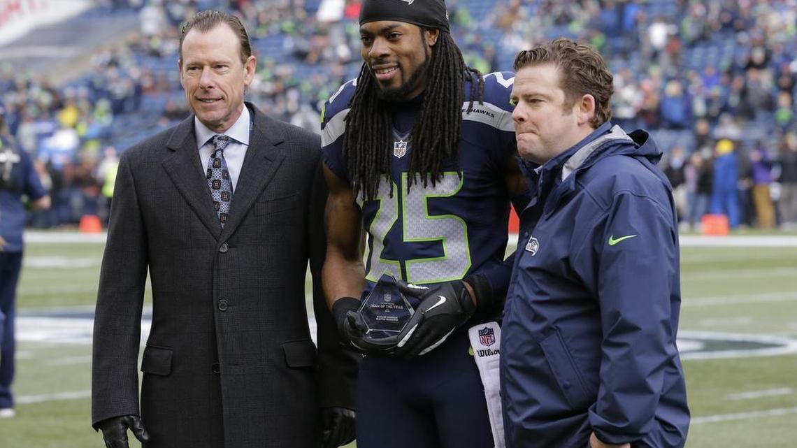 Richard Sherman (25) poses with general manager John Schneider, right, and team president Peter McLoughlin after the cornerback was named the Seahawks’ “Man of the Year” before last weekend’s game against the Browns. “I’ve become more patient,” Sherman says.