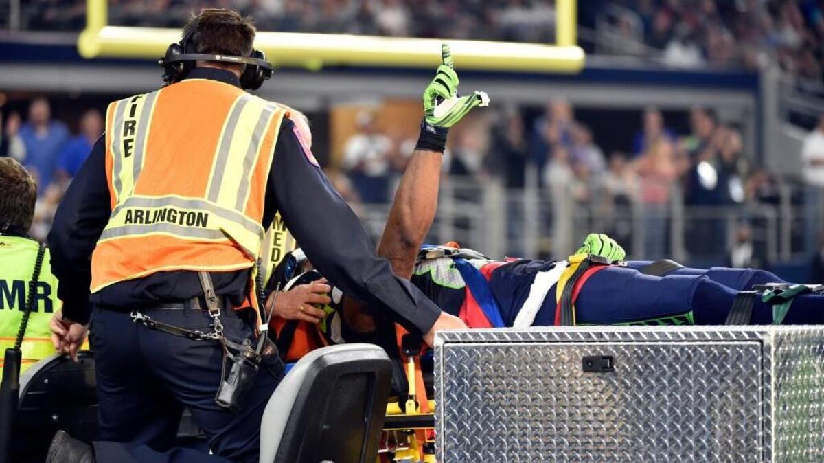 Seattle Seahawks’ Ricardo Lockette signals to the crowd as he is carted off the field strapped to a spine board. Lockette suffered a sore neck and concussion near the end of the first half after taking a hit by Dallas’ Jeff Heath.