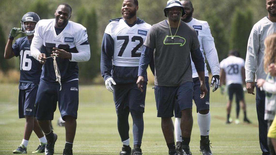 Seattle Seahawk Michael Bennett (72) walks off the field smiling with teammates (from left) Tyler Lockett (16), Cliff Avril and Ahtyba Rubin following the opening day of training camp Saturday in Renton. Bennett had been vocal about wanting a new contract.