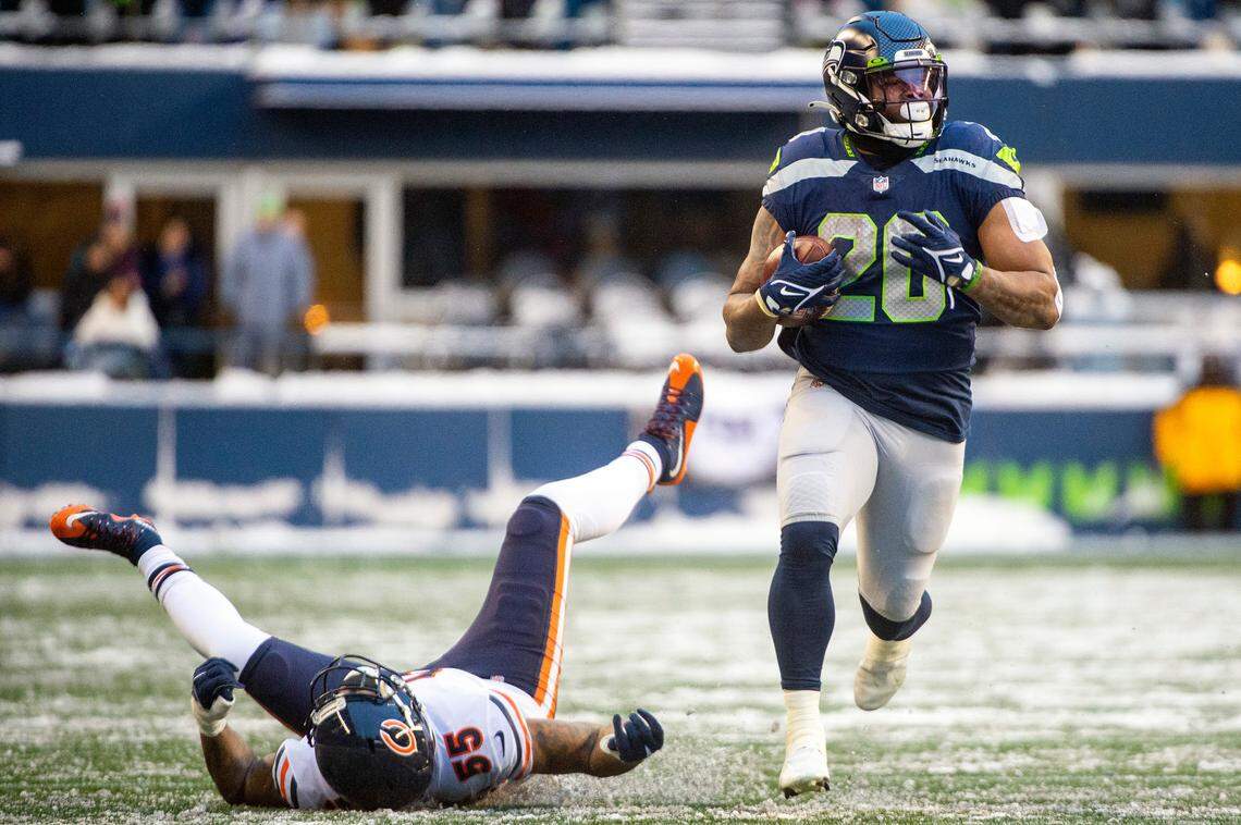 Seattle Seahawks running back Rashaad Penny (20) runs down the sideline after stiff-arming Chicago Bears linebacker Bruce Irvin (55) during the fourth quarter of an NFL game on Sunday afternoon at Lumen Field in Seattle.