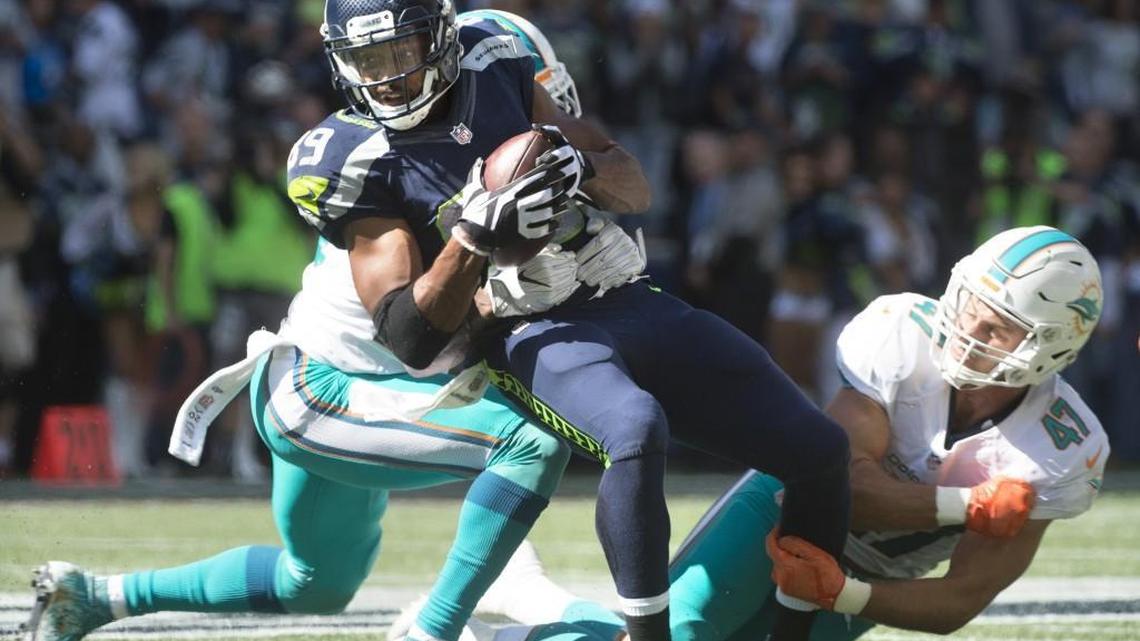 Seattle’s Doug Baldwin is wrapped up by Dolphins safety Reshad Jones (left) and linebacker Kiko Alonso.