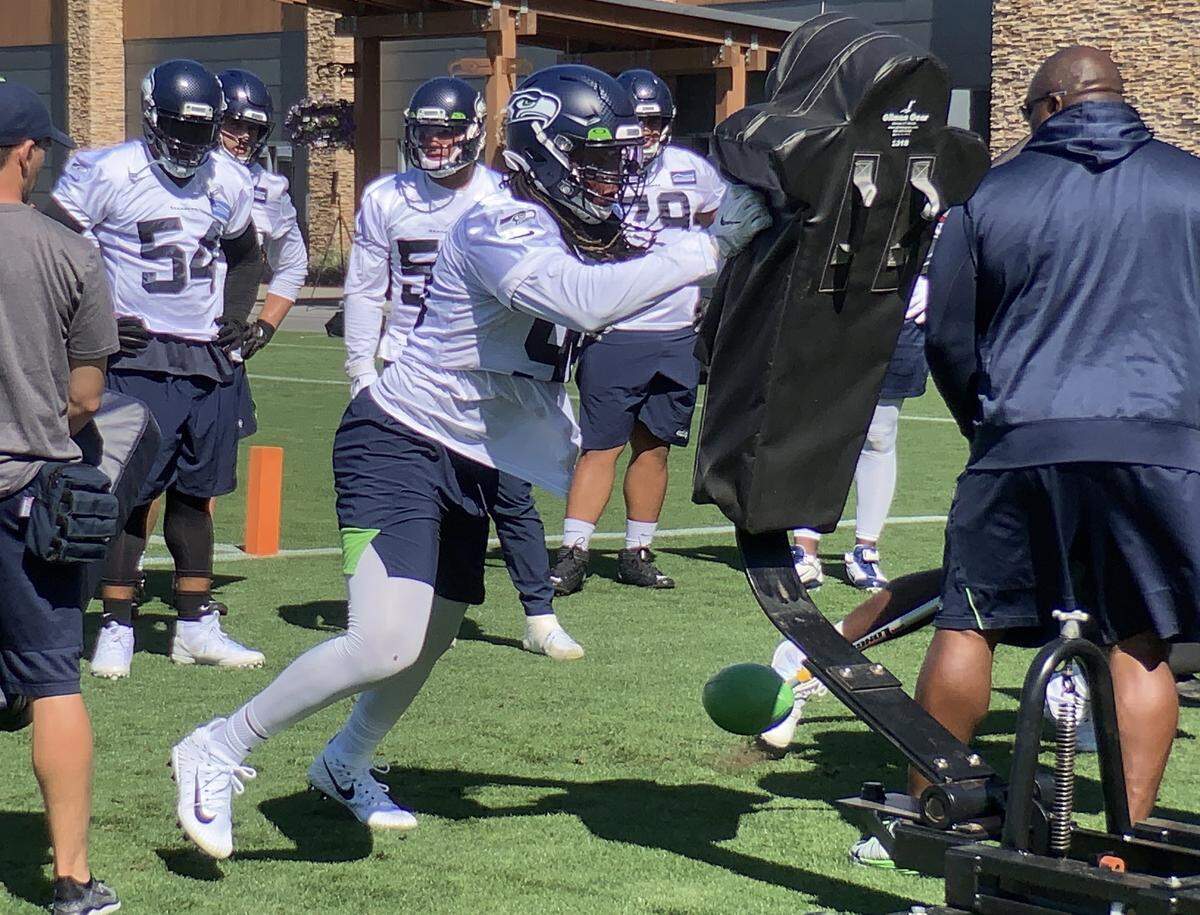 All-Pro Bobby Wagner (54) watches top sack man Ziggy Ansah (pushing into sled) drill early in the defensive end’s first practice with the Seahawks. Seattle signed the 2015 Pro Bowl pass rusher in May. He has been recovering from shoulder surgery last season that ended his time with the Detroit Lions.