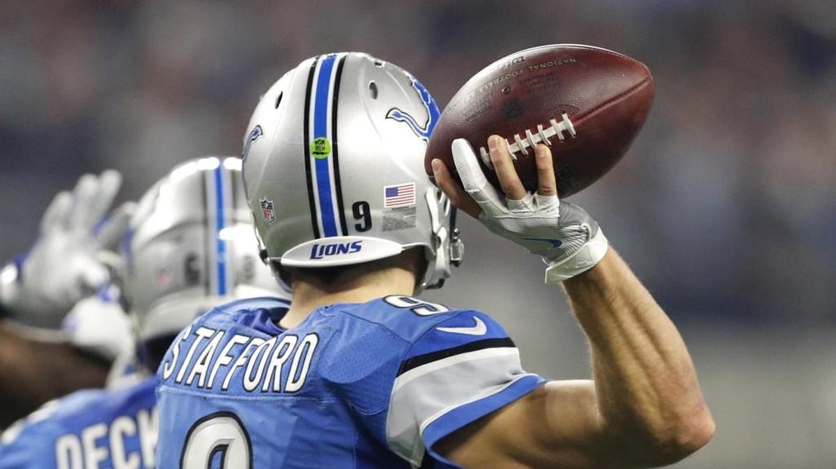 The throwing hand and glove of Detroit Lions quarterback Matthew Stafford is highlighted as he throws a pass.