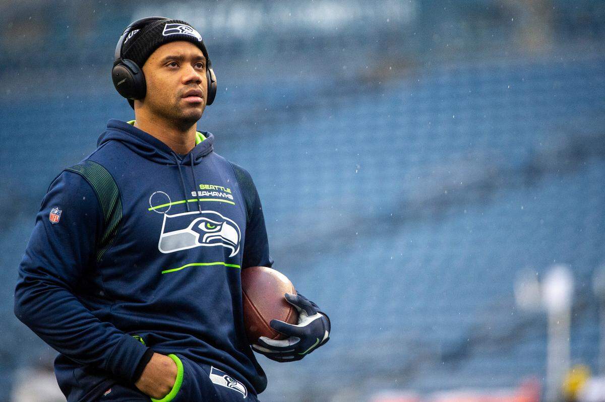 Seahawks quarterback Russell Wilson watches other NFL games be played on the big screen as he warms up prior to the start of Seattle’s game against the Detroit Lions on Sunday, Jan. 2, 2022, at Lumen Field in Seattle.
