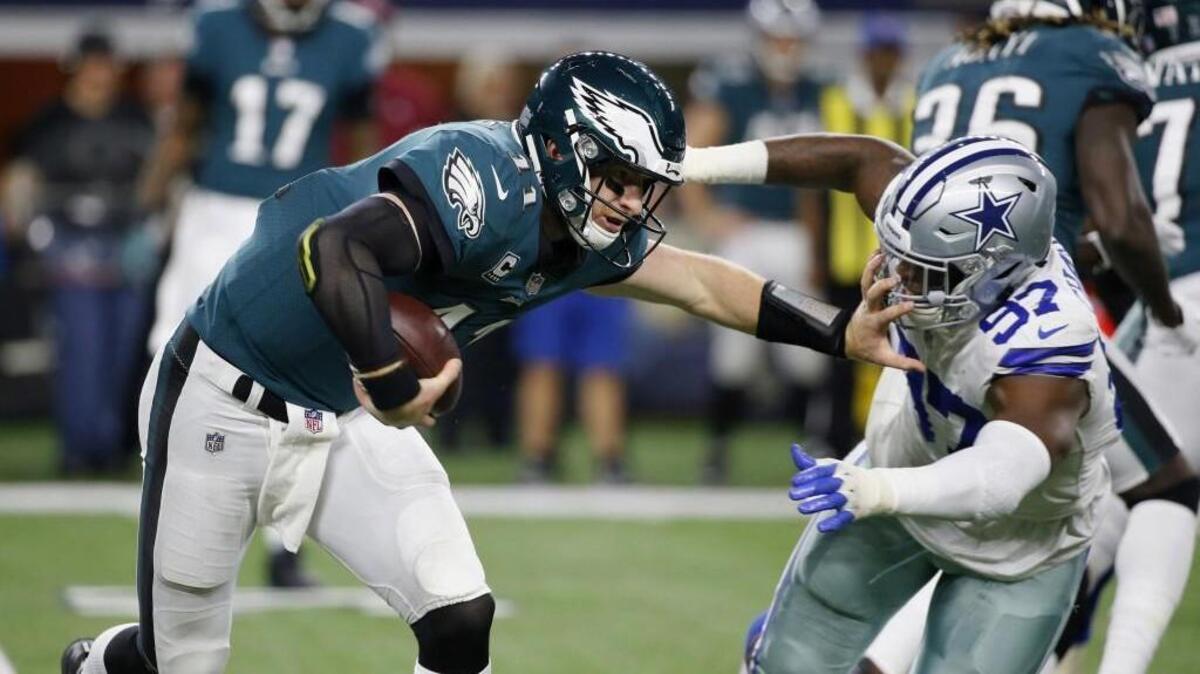 Philadelphia Eagles’ Carson Wentz fends off Dallas Cowboys' Taco Charlton, right, to gain some yards. Wentz, the second-year quarterback, has helped the Eagles lead the NFL in points scored (351), offensive touchdowns (37) and wins by double-digit margins (seven).