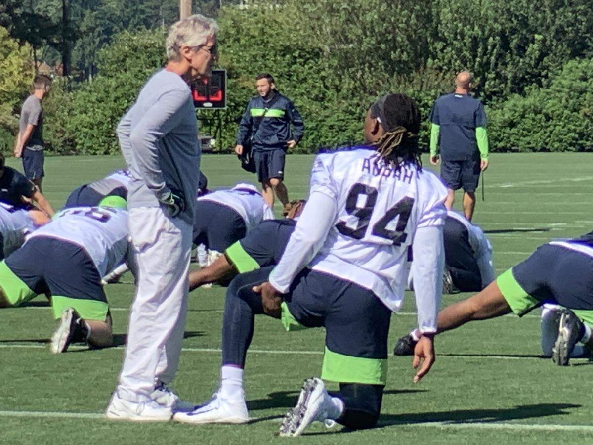 Defensive end Ziggy Ansah, wearing his new-old jersey number 94 he wore for six seasons with the Detroit Lions, talks with coach Pete Carroll at the start of the Seahawks’ light practice Wednesday.