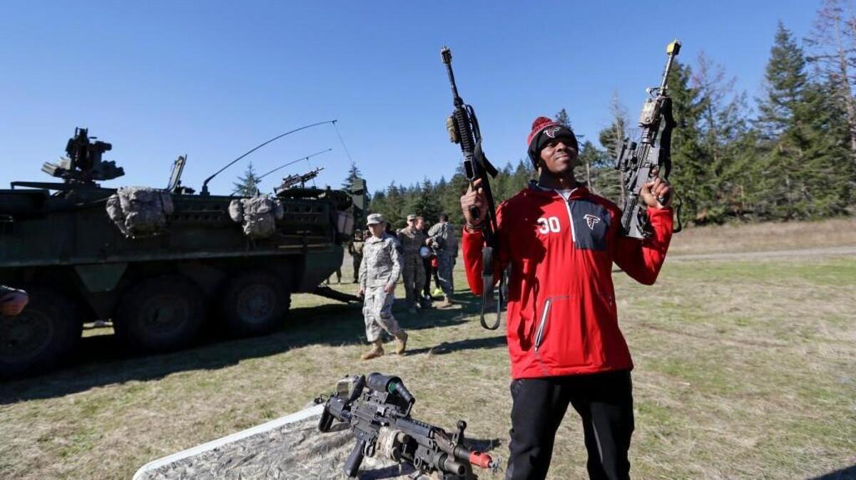 Atlanta’s Deji Olatoye holds a pair of rifles as players are given a hands-on orientation of training for U.S. Army soldiers working to earn an Expert Infantry Badge at Joint Base Lewis McChord. , Wash. The team traveled directly to Seattle after their football game Sunday in Denver, ahead of playing the Seattle Seahawks on Sunday. (AP Photo/Elaine Thompson)