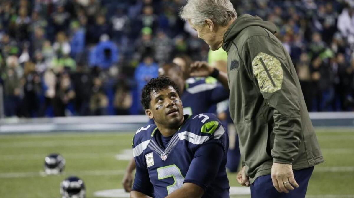 Seattle quarterback Russell Wilson, left, talks with head coach Pete Carroll before a game, Sunday against Arizona.