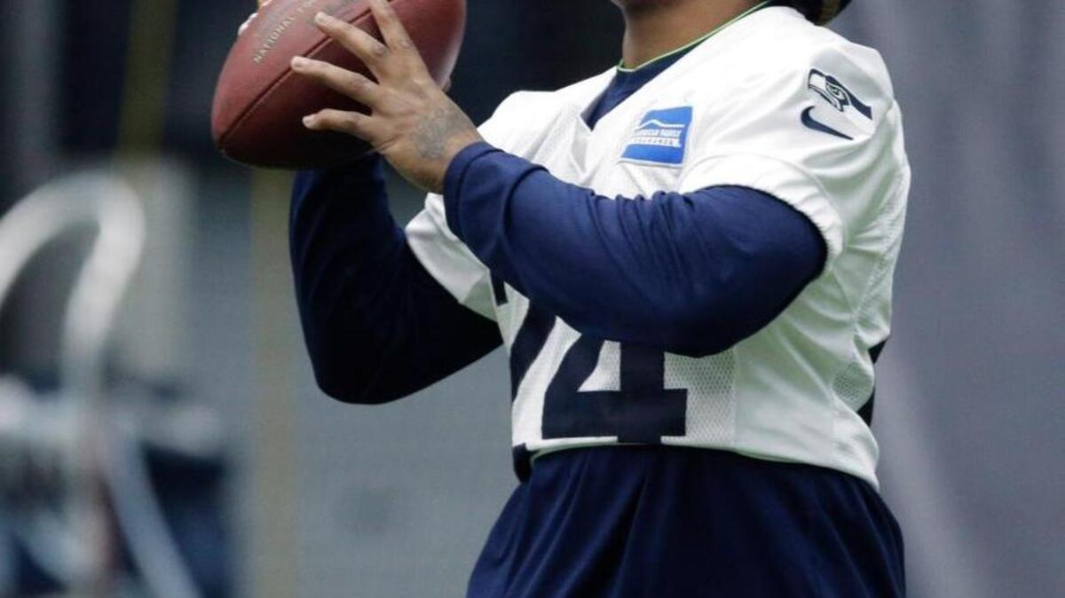 Seattle’s Marshawn Lynch holds a candy cane in his mouth as he warms up Wednesday before practice. Lynch has been recovering since having abdominal surgery in November.