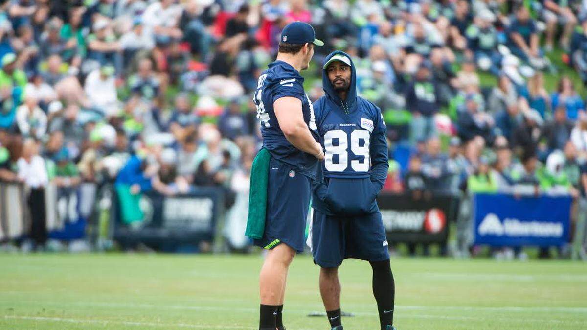 Pro Bowl wide receiver Doug Baldwin (89), wearing a sleeve again over his injured left knee, talks to guard J.R. Sweezy (64) while missing practice for the fifth consecutive time Friday at Seahawks training camp in Renton.
