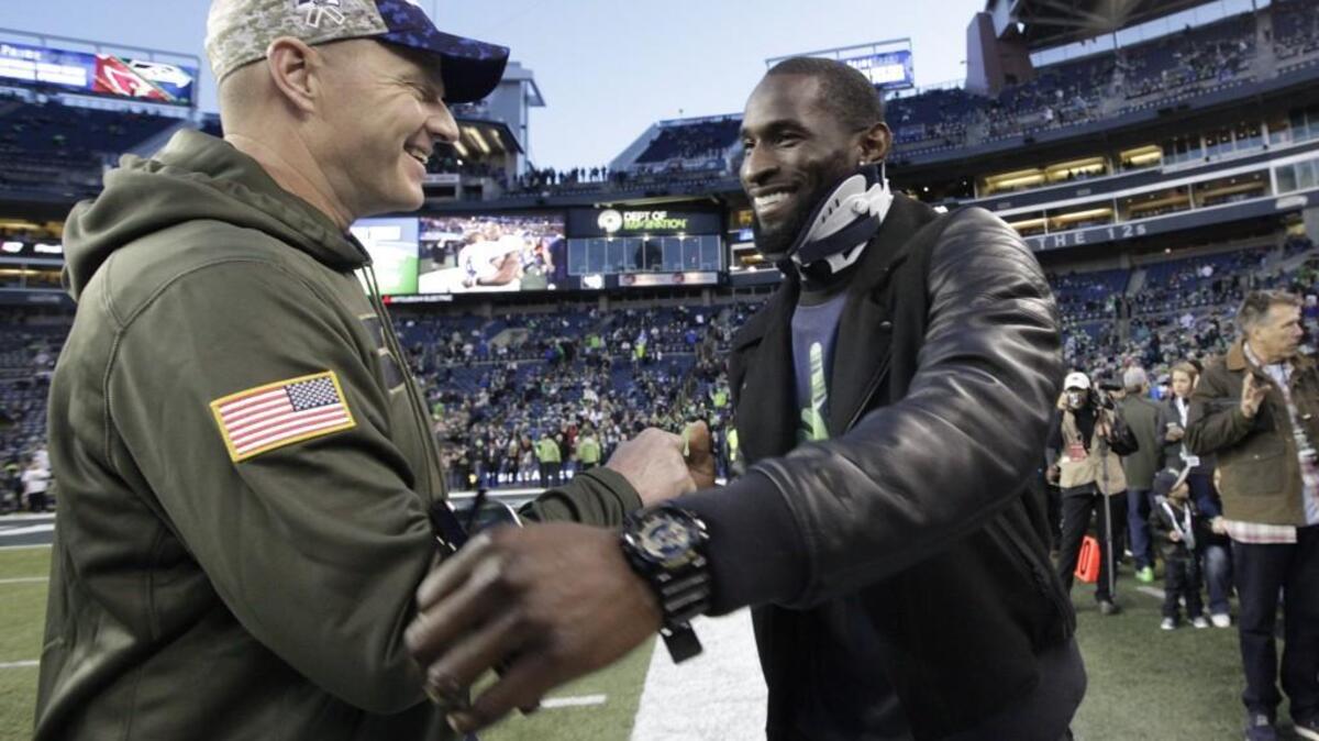 Injured Seattle Seahawks wide receiver Ricardo Lockette, right, wears a neck brace as he greets Seahawks offensive coordinator Darrell Bevell, left, as he arrives at CenturyLink Field before Sunday’s game against the Arizona Cardinals.