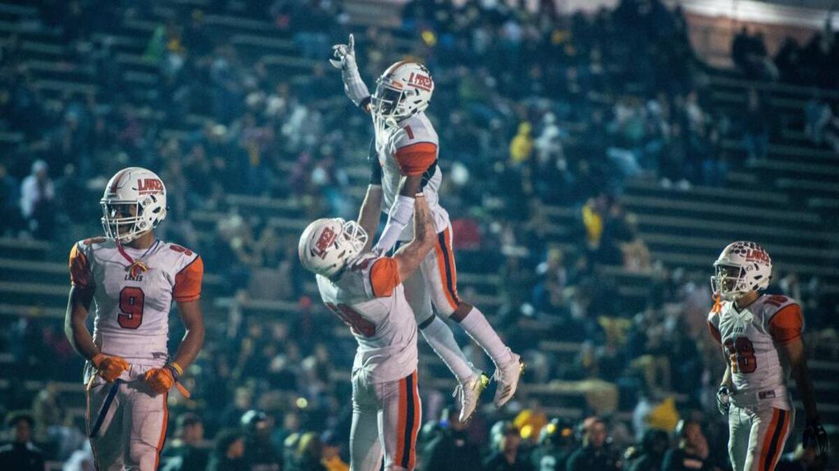 Lakes’ Alan Fischer (58) hoists Daeshawn Wayne (1) into the air after Wayne’s touchdown catch in the fourth quarter. Lincoln high school played Lakes high school in a football game at the Lincoln Bowl in Tacoma, Wash., on Friday, Oct. 19, 2018.