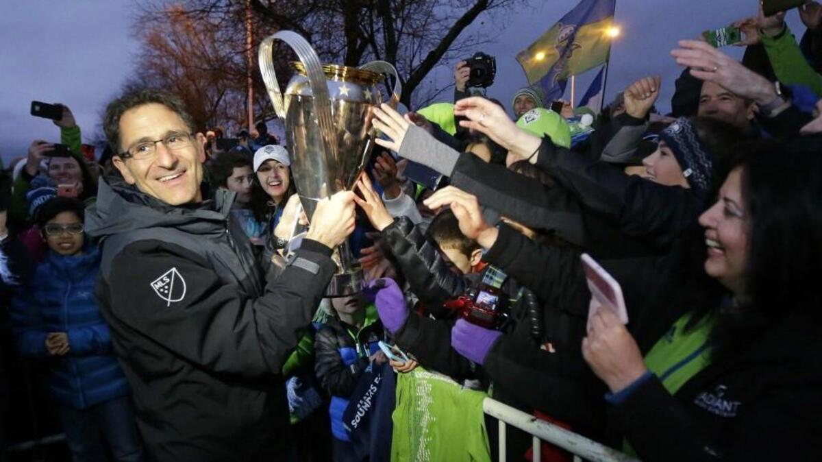 Seattle Sounders owner Adrian Hanauer, left, holds the MLS Cup as he greets fans at the King County Airport in Seattle, Sunday, Dec. 11, 2016, after the MLS soccer team returned from Toronto, where they beat Toronto FC Saturday to win the MLS Cup.
