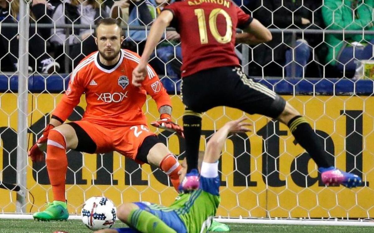 Seattle Sounders goalkeeper Stefan Frei, upper left, position to stop a shot by Atlanta United midfielder Miguel Almiron (10) as Almiron leaps over Sounders' Osvaldo Alonso in the second half of an MLS soccer match, Friday, March 31, 2017, in Seattle. The match ended in a 0-0 tie.