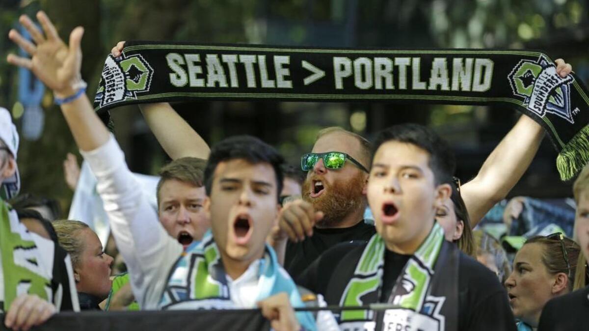 FILE - In this Aug. 27, 2017, file photo, a Seattle Sounders supporter holds up a scarf as he takes part in the traditional March to the Match before an MLS soccer match against the Portland Timbers in Seattle. The Timbers host the Sounders on Sunday in the 100th meeting between the two rivals from the Pacific Northwest. (AP Photo/Ted S. Warren, File)