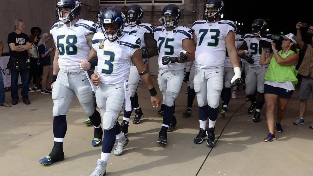 Seattle Seahawks quarterback Russell Wilson (3) and center Justin Britt (68) walk to the field with arms linked after the national anthem had been played before an NFL football game between the Seahawks and the Tennessee Titans on Sept. 24, 2017, in Nashville, Tenn.