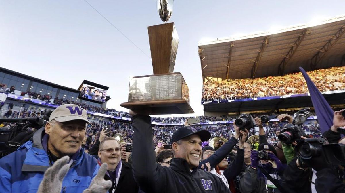Washington coach Chris Petersen hefts the Apple Cup trophy as Washingotn Gov. Jay Inslee, left, applauds after presenting it to him after Washington defeated Washington State 45-10 in an NCAA college football game Friday, Nov. 27, 2015, in Seattle.