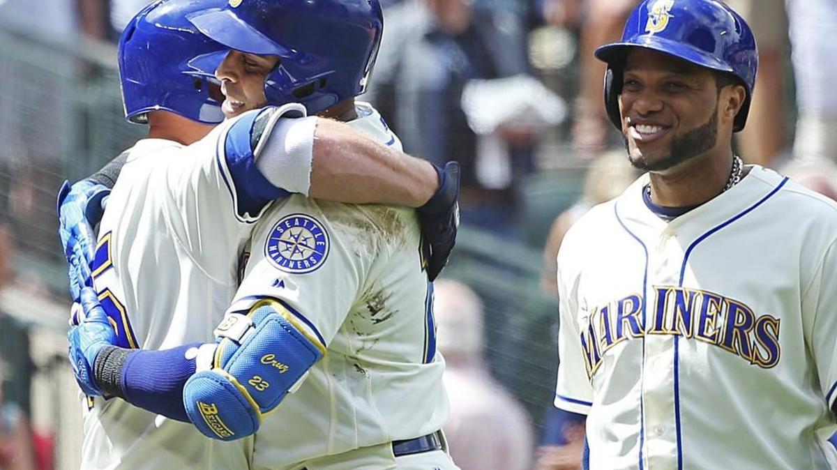 Seattle Mariners designated hitter Nelson Cruz, center, gets a hug from Kyle Seager at home plate after knocking in Robinson Cano, at right, with his two-run home ru in the fourth inning against the Oakland Athletics on Sunday, July 9, 2017, at Safeco Field.