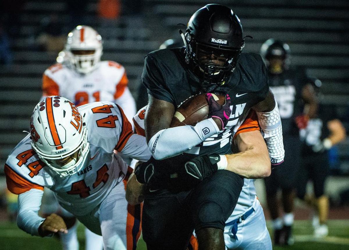 Lakes players tackle Lincoln’s Julien Simon (24) in the first quarter. Lincoln high school played Lakes high school in a football game at the Lincoln Bowl in Tacoma, Wash., on Friday, Oct. 19, 2018.