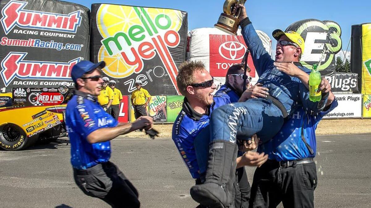 Funny car driver Tommy Johnson Jr. is hoisted by his crew Sunday. Johnson upset the favorite in the semifinals and won the finals on a holeshot.