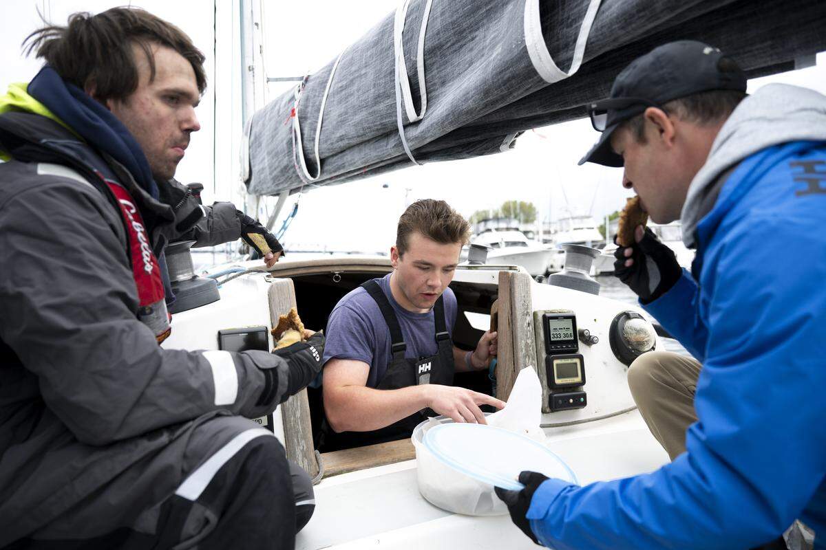 Grayson Botelho, Adam White and Matt Tagles grab a race cookie on the Grace E before The Corinthian Yacht Club of Tacoma Late Spring Windseekers #1 race on Commencement Bay, on Wednesday, May 13, 2026, in Tacoma.