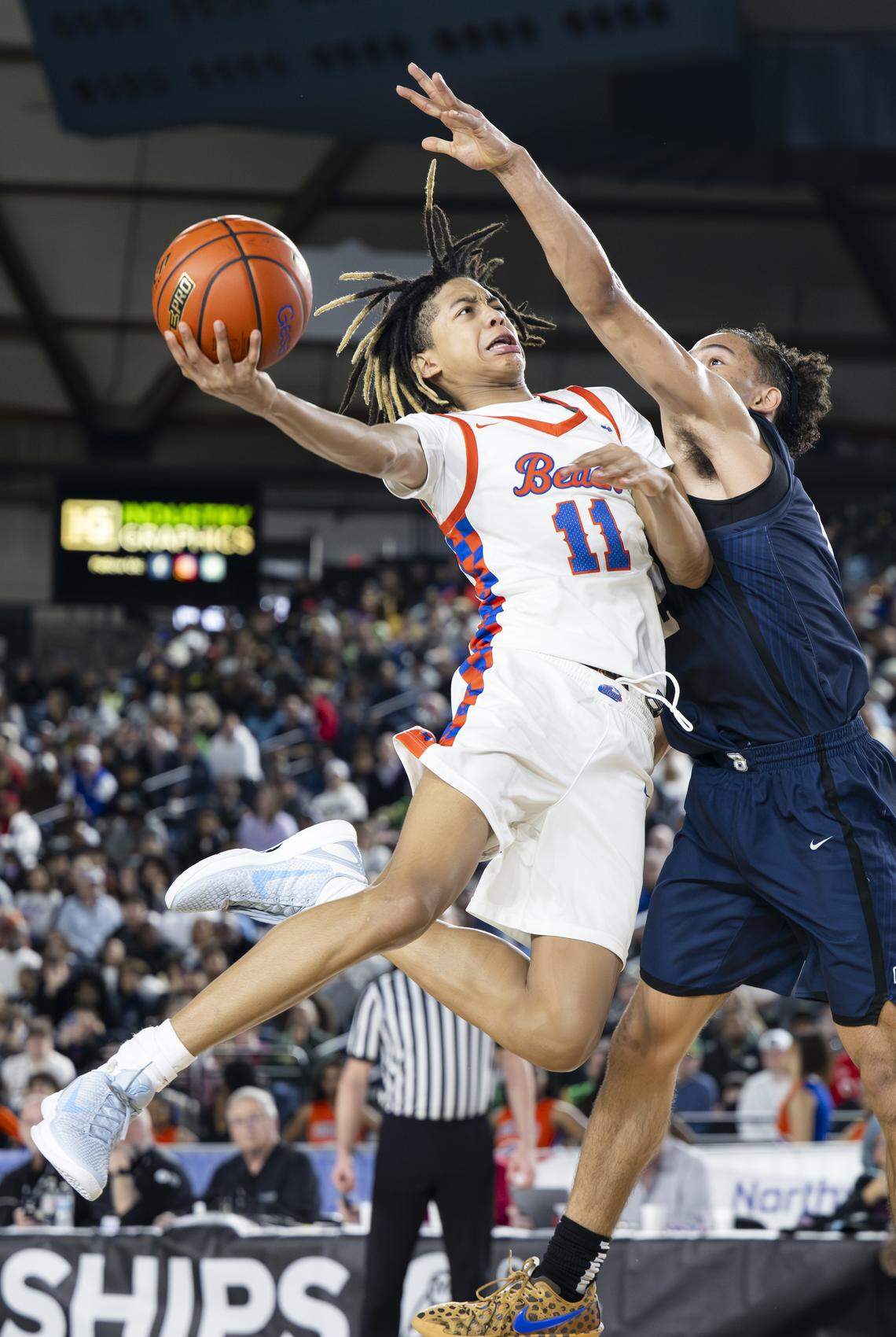 Rainier Beach guard JJ Crawford (11) is fouled by Bellarmine Prep forward Birk Johnston (12) during the semifinal round of the 3A State Tournament at the Tacoma Dome, on Friday, March 6, 2026, in Tacoma, Wash.